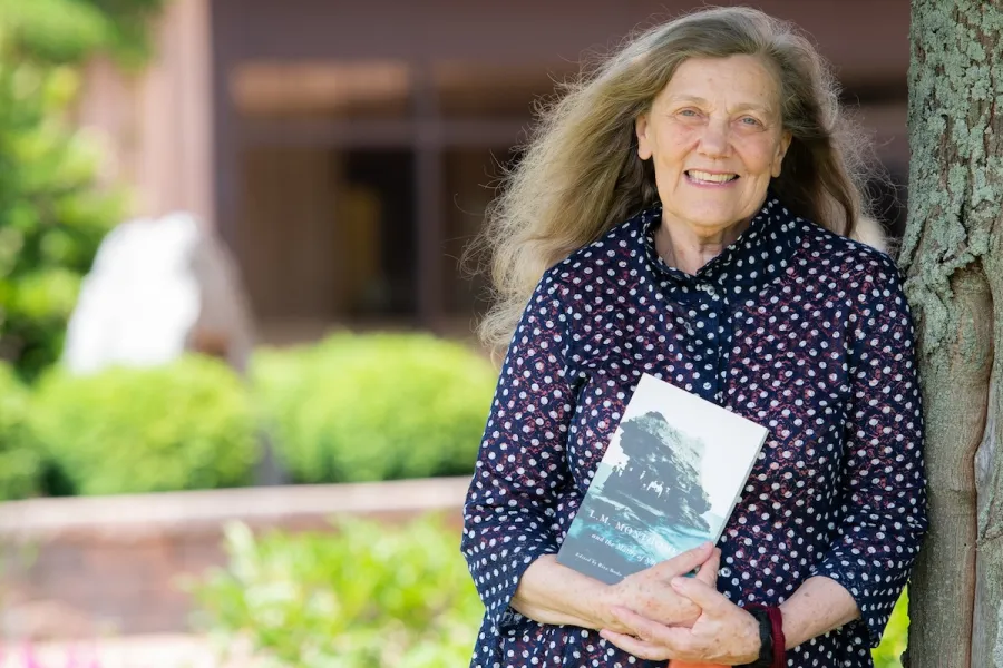 dr. jean mitchell photographed outside beside a tree, holding her book 