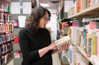 dr. kate scarth reading a book in the stacks of UPEI's robertson library