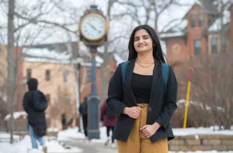 a UPEI student in the quadrangle by a clock