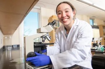 a UPEI biology student in a laboratory using a microscope